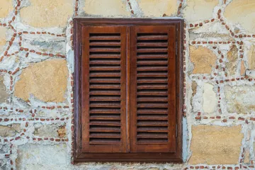 Closeup wall of a stone house with wooden windows and shutters Old european architecture